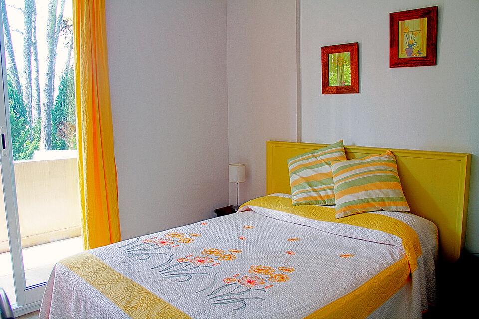 Dormitorio principal con la ventana abierta a los troncos de los pinos