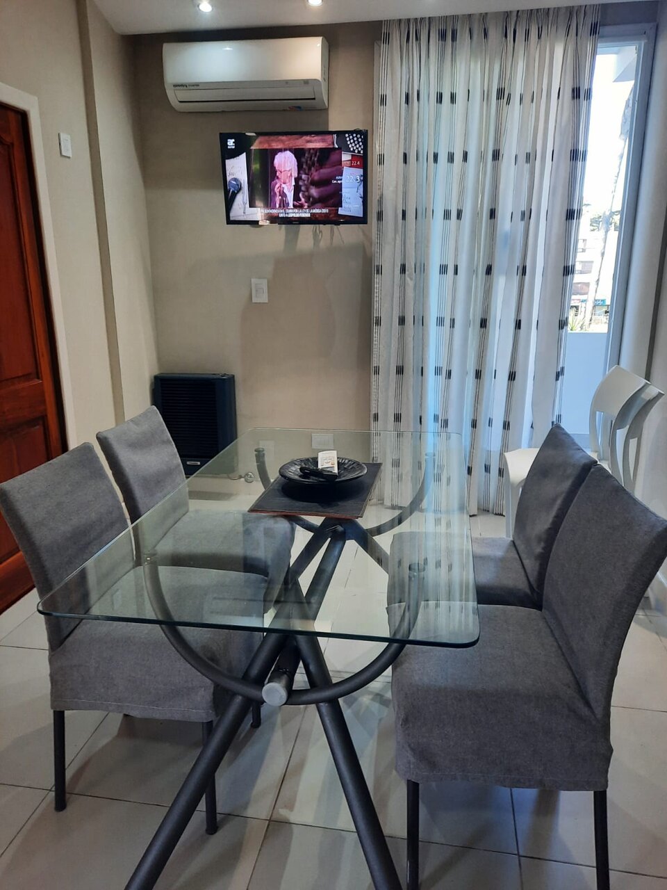 Comedor con la mesa de vidrio y el ventanal al balcón