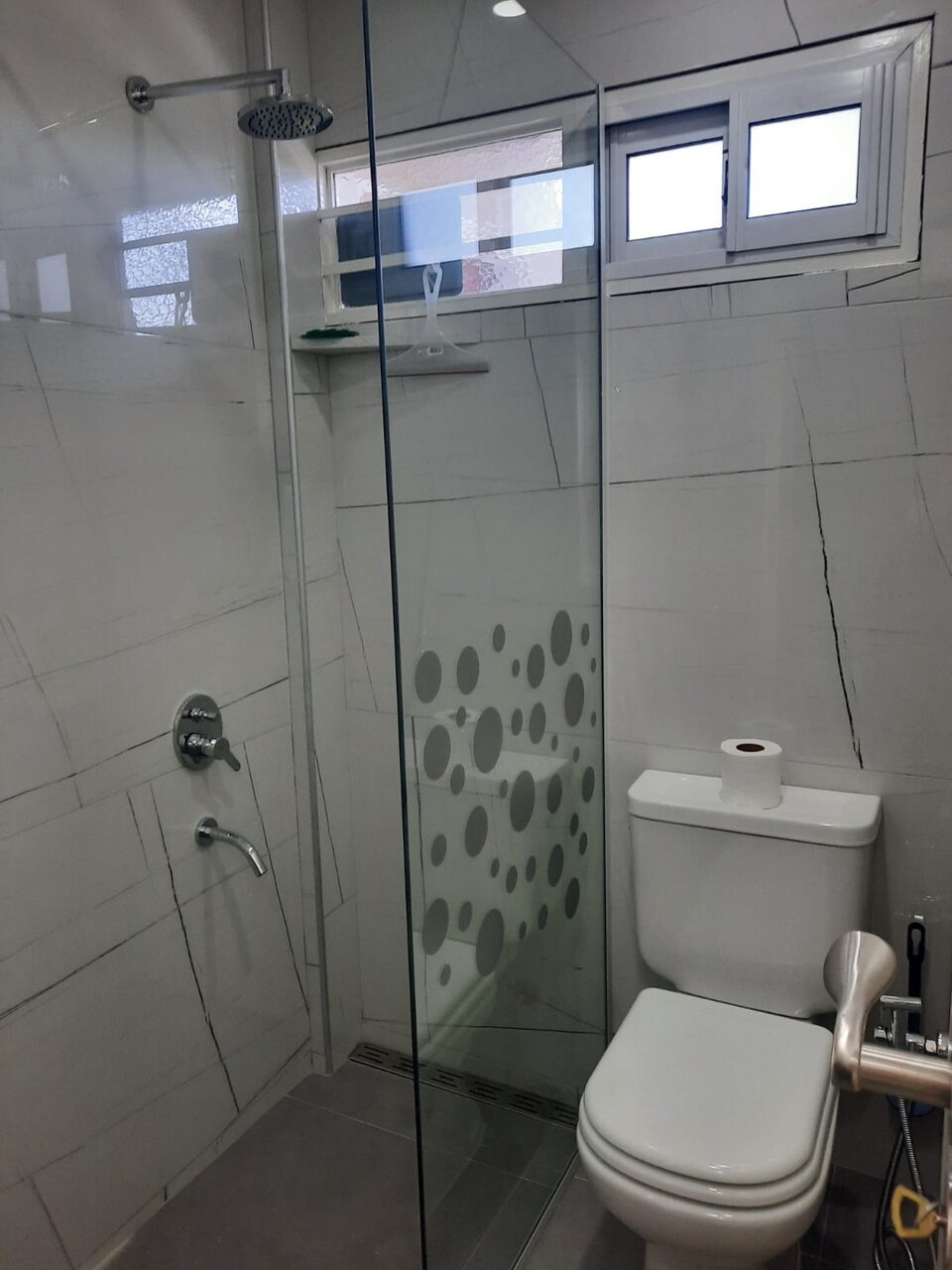 Baño en suite en porcelanato de gran formato, con mampara de vidrio y lluvia