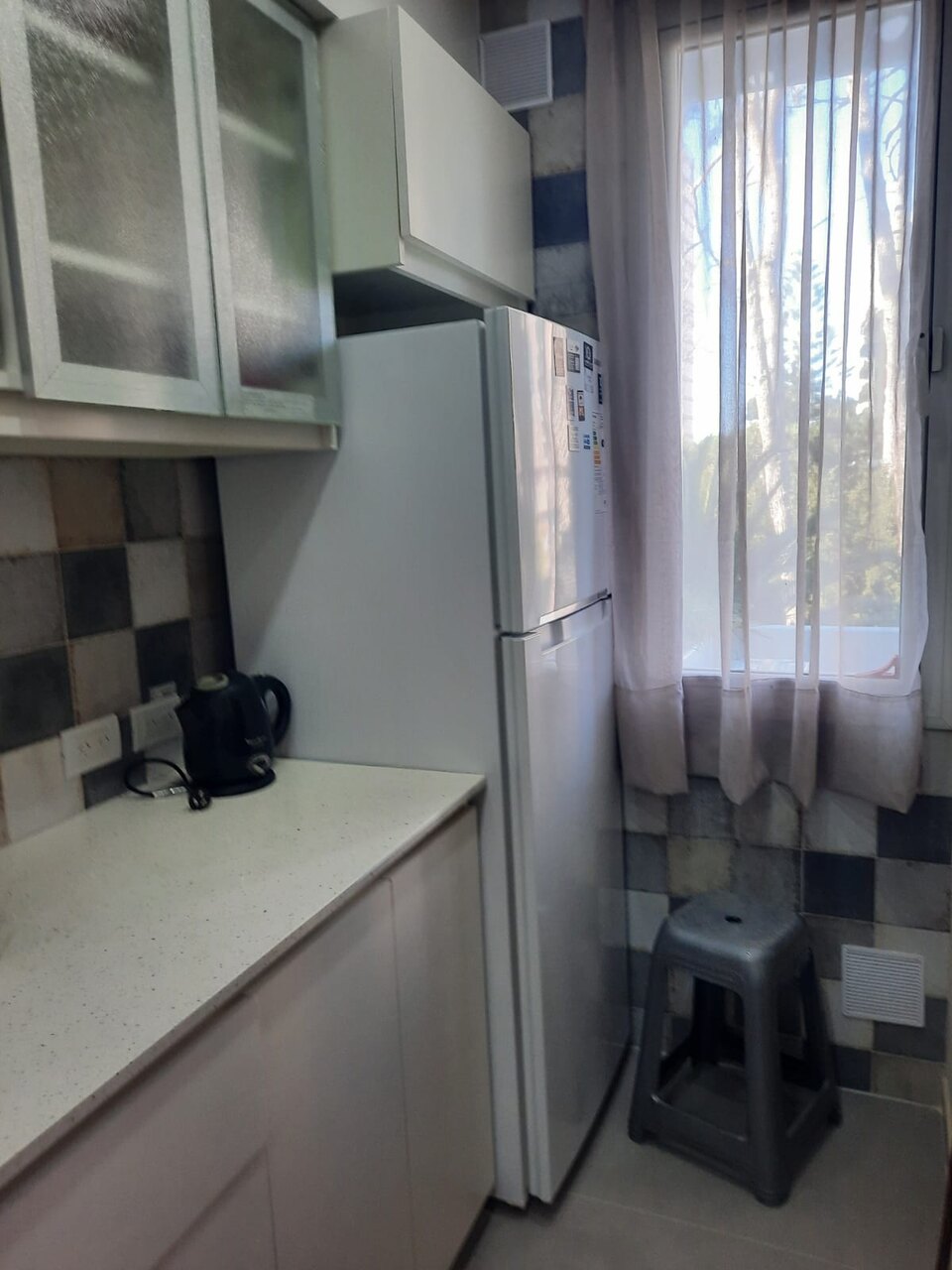Ventana de la cocina con los pinos detrás de la cortina